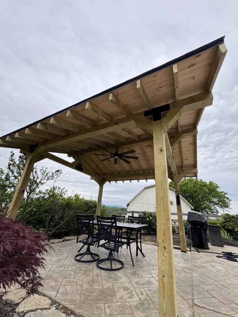 Timber frame pavilion with wood ceiling, ceiling fan, and outdoor dining on stamped concrete patio overlooking East Tennessee mountain views
