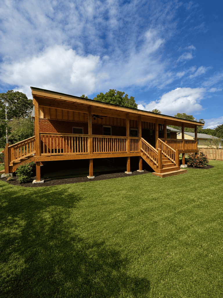 Custom full length covered back porch with stained wood deck, railings, dual staircases, and ceiling fan addition on brick home in Knoxville Tennessee