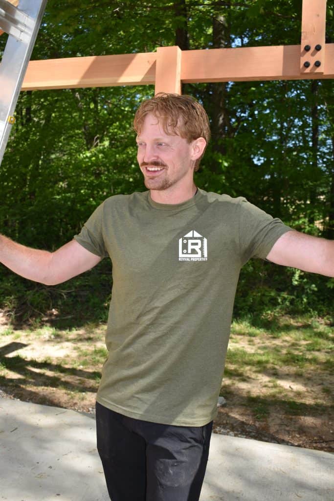 Logan Dixon, owner of Revival Properties on a Job Site Standing bya ladder