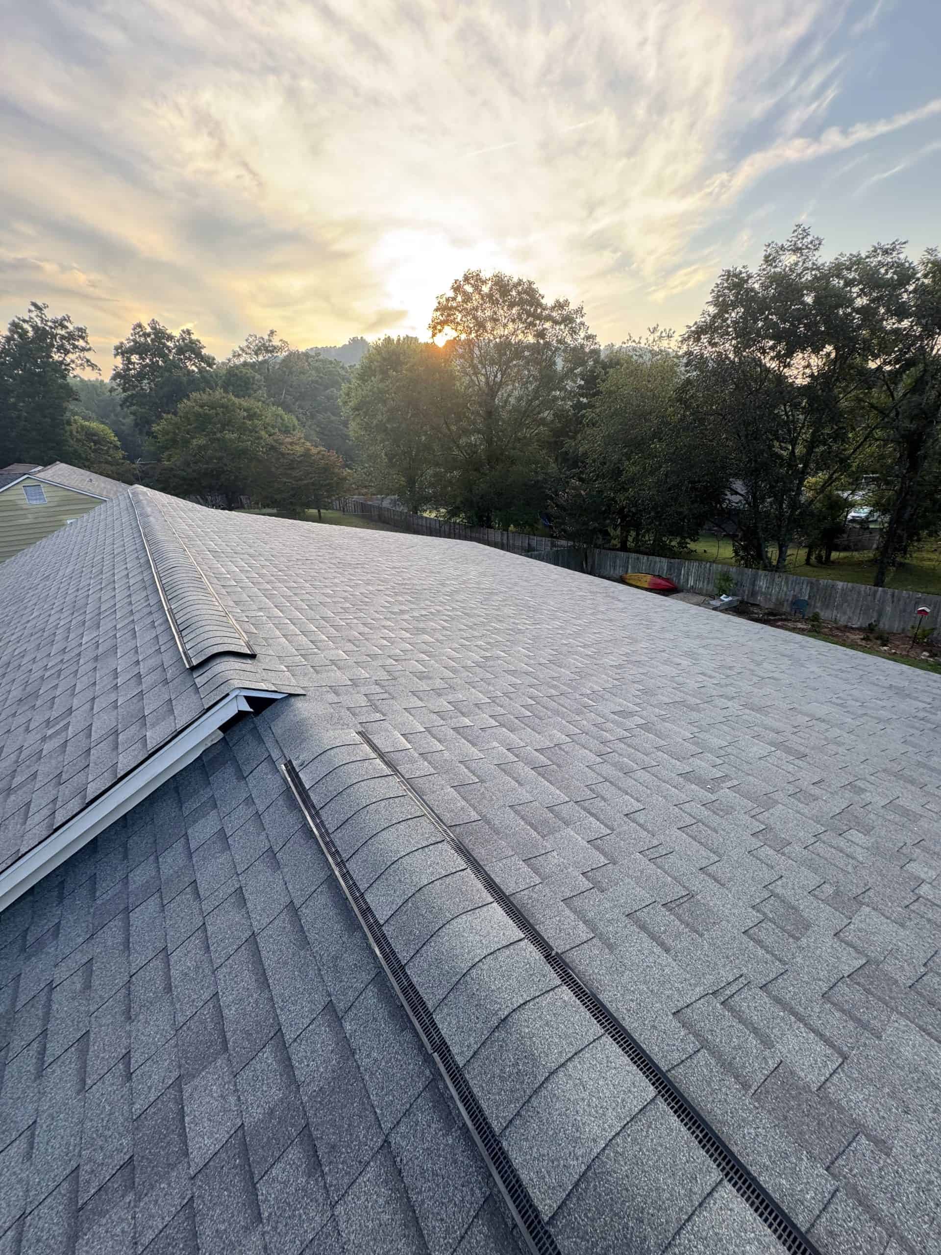 Completed architectural shingle roof replacement by Revival Properties in Knoxville TN showing clean installation with ridge vent at sunset