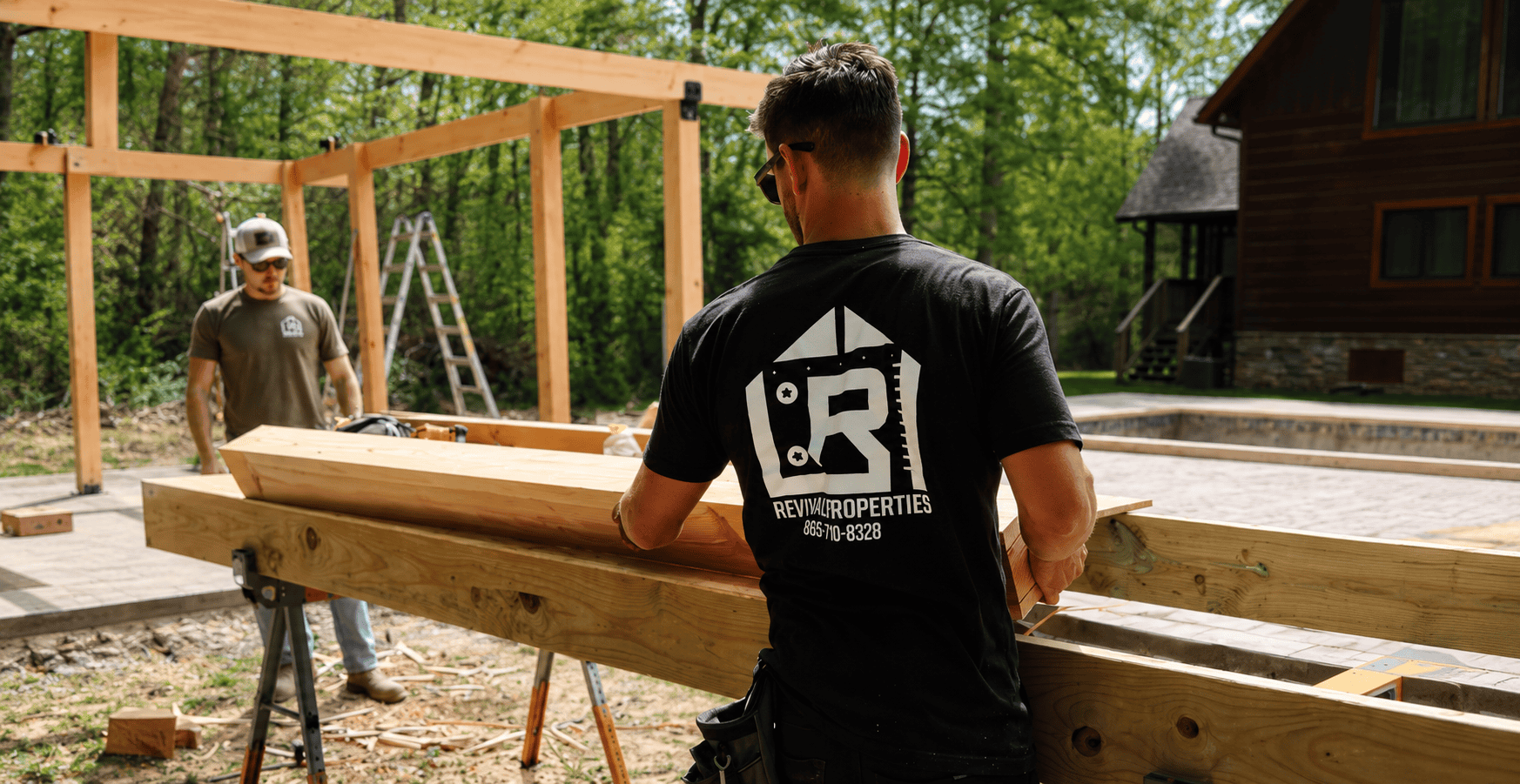 Revival Properties team members building a custom pergola structure outdoors with large timber beams and luxury craftsmanship in a wooded residential setting near Knoxville Tennessee