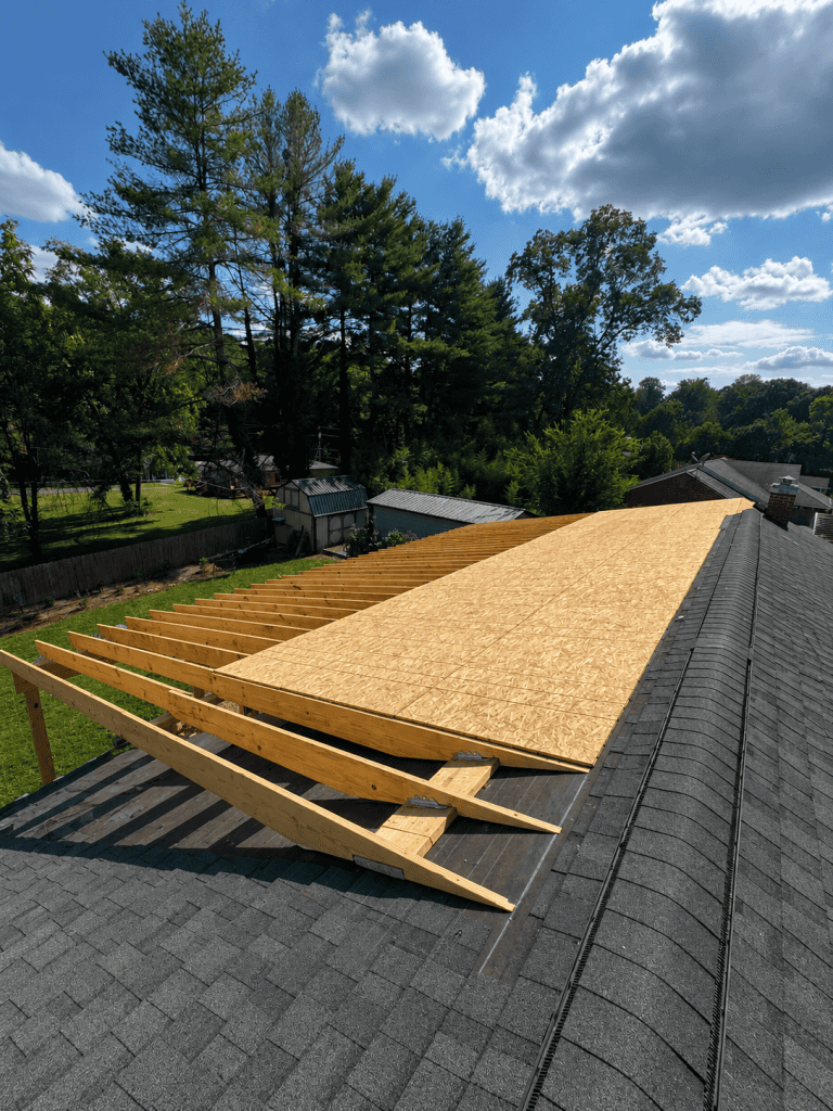 Roof framing and plywood sheathing installation on a residential property.