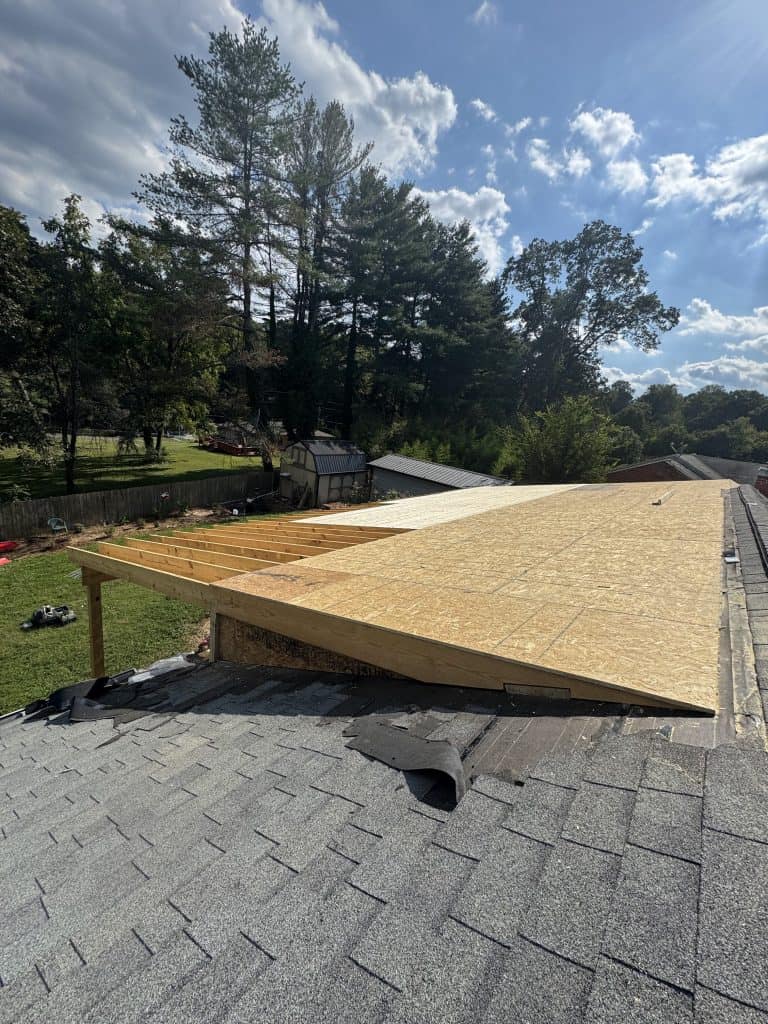 Roof extension framing and OSB decking in progress alongside existing shingles during roof remodel by Revival Properties in Knoxville Tennessee