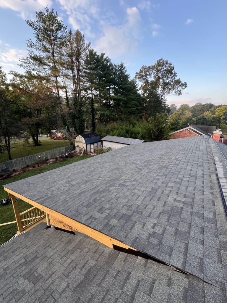 Completed gray architectural shingle roof replacement by Revival Properties in Knoxville TN with new deck framing visible on brick home below